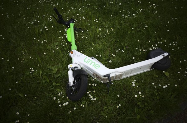 E-scooter laid on a meadow in the bike rental of the company Lime