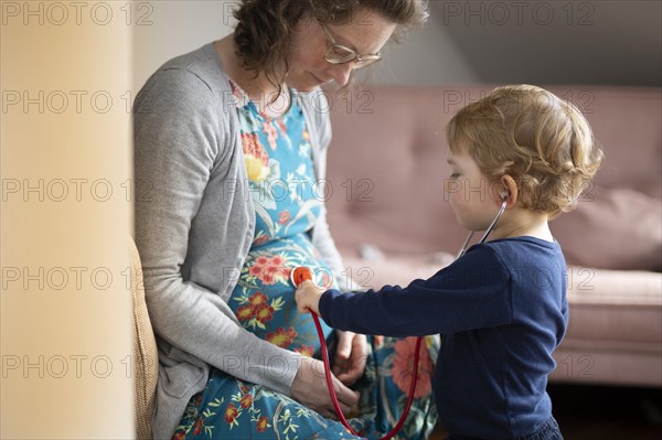 Subject: Family planning. Child listening with a stethoscope on the pregnant mother's belly.