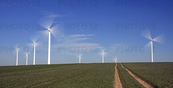 Spinning blades of wind turbines at windfarm against blue sky