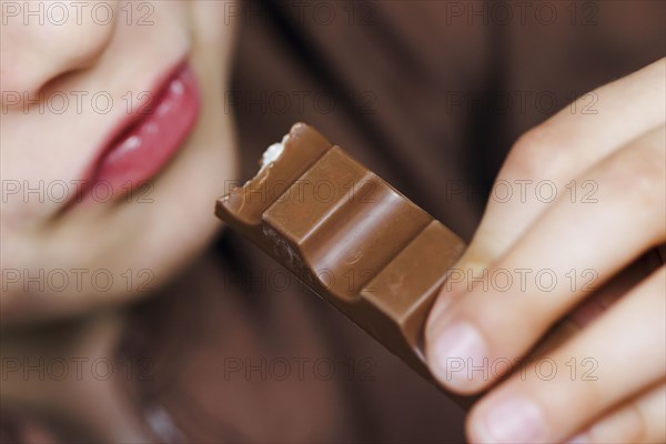 Symbolic photo on the subject of eating chocolate. A boy takes a bite from a chocolate bar. Berlin