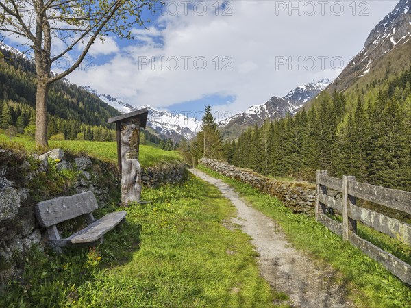 Wayside shrine with bench in front of mountain scenery