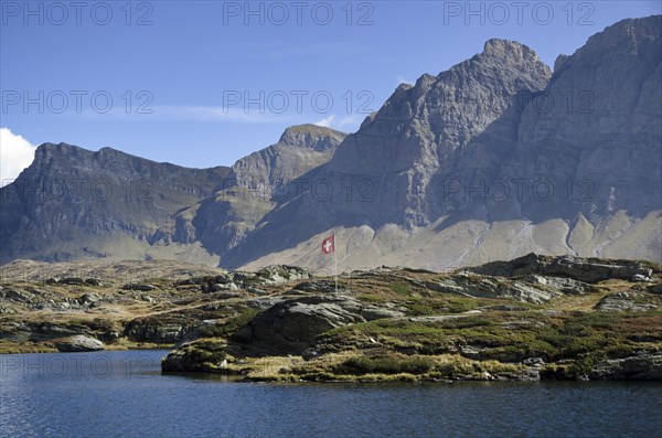 Panoramic view over mountain and an alpine lake with a Swiss flag