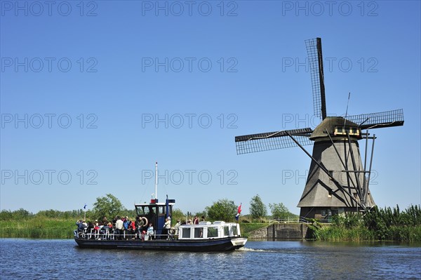 Tourists on sightseeing boat and thatched polder windmill at Kinderdijk