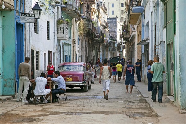 Busy street scene and red old 1950s vintage American car