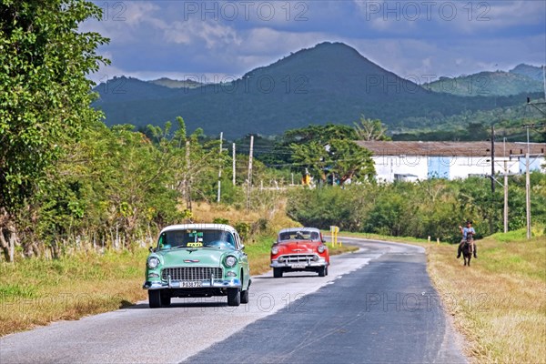 Vintage Chevrolet taxi and red classic American car driving along Circuito Sur