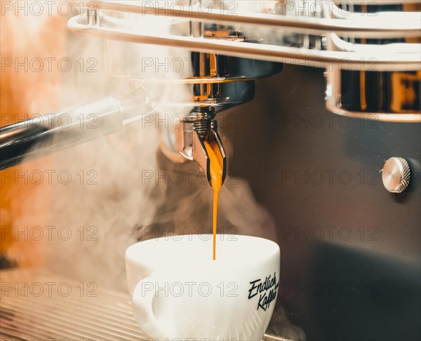 Hot coffee runs out of a portafilter into a coffee cup