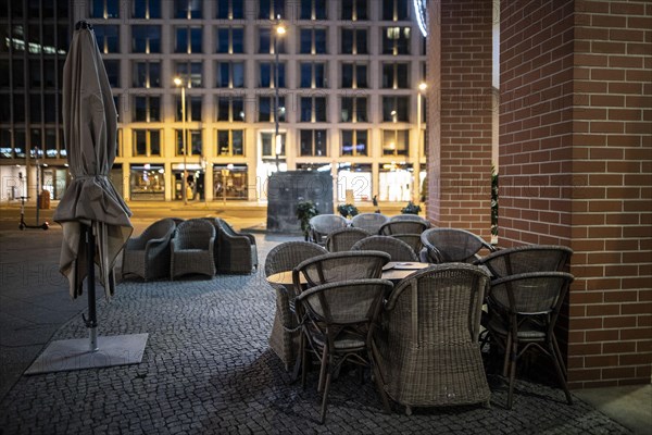 Unused furniture standing in front of a cafe at Potsdamer Platz in Berlin in the evening