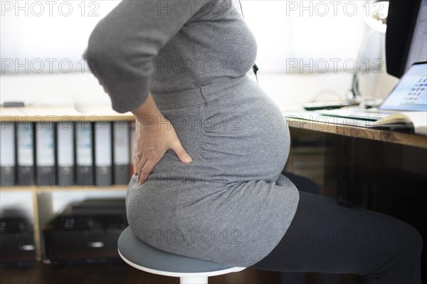 Young pregnant woman in pain at work