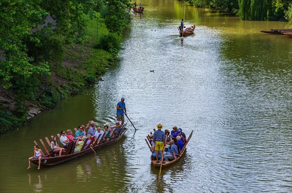 Tourists and excursionists in crowded punting barges are moved up and down the Neckar in front of the Neckarfront