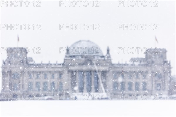 The Reichstag building is silhouetted against snowfall in the government district in Berlin