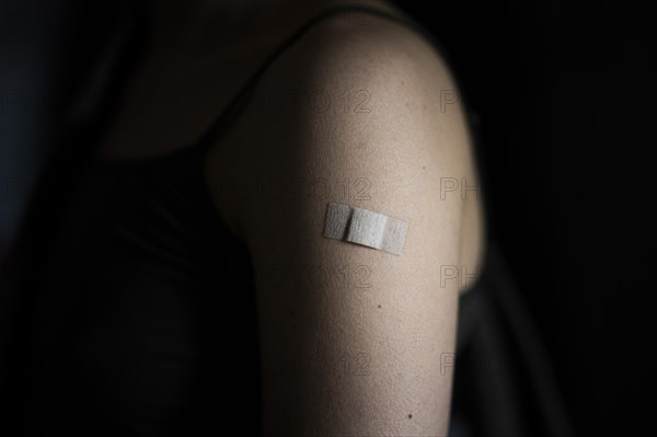 A plaster is stuck on the left upper arm of a woman vaccinated against Corona