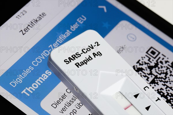 A negative SARS-CoV-2 Rapid Ag Antigen rapid test lies on a smartphone displaying an EU digital COVID certificate. Berlin