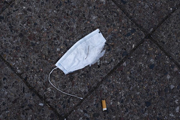 A discarded mouth-nose protection lies on the ground