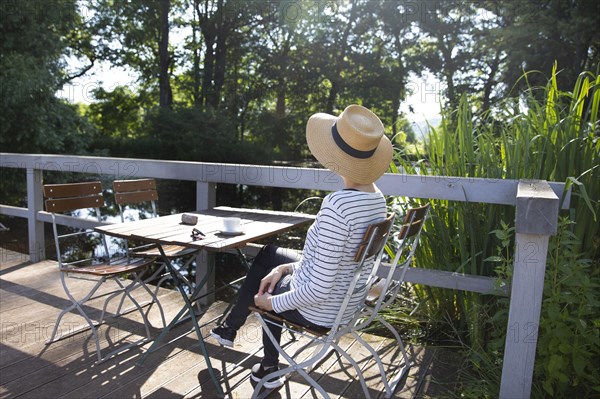 Woman sitting by a pond drinking coffee