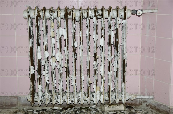Old rusty radiator with pink tiles in background