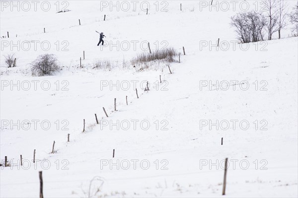 A boy carries skis up a slope in Koenigshain