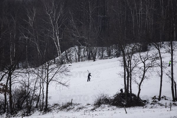 A boy carries skis up a slope in Koenigshain