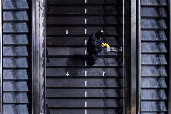 A cleaner wipes a staircase marked with arrows for the respective walking directions
