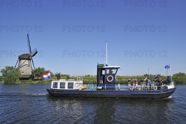 Tourists on sightseeing boat and thatched polder windmill at Kinderdijk