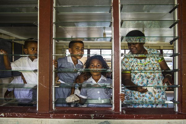 School boy cleaning the windows of their school