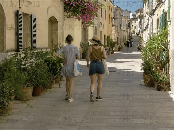 Two walking girls on the street in the old town of Alcudia