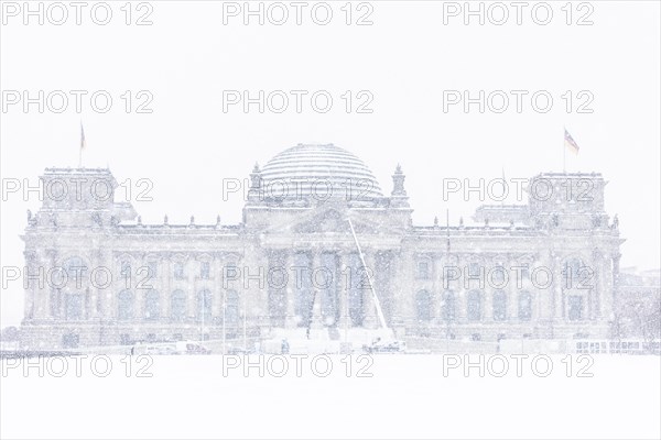 The Reichstag building is silhouetted against snowfall in the government district in Berlin