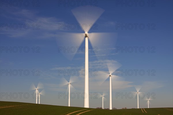 Spinning blades of wind turbines at windfarm against blue sky