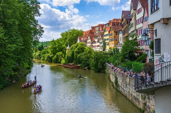 Tourists and excursionists in crowded punting barges are moved up and down the Neckar in front of the Neckar front under the eyes of numerous spectators on the remains of the city wall