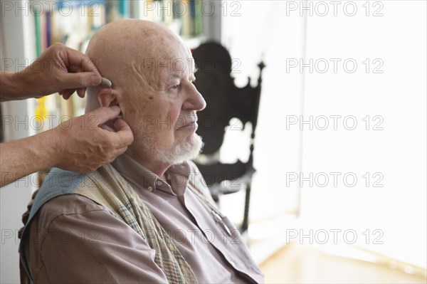 Help in old age. An old man gets a hearing aid fitted