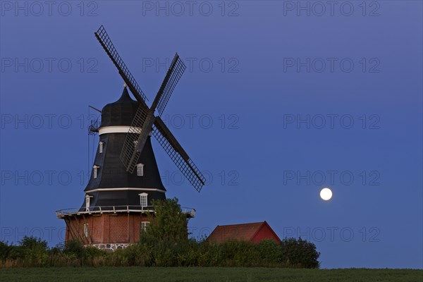 Traditional windmill in field at full moon