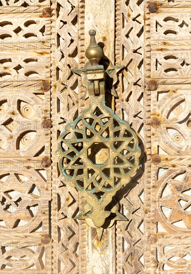 Ornate design brass knocker wooden doorway