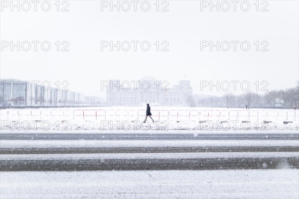 The Reichstag building is silhouetted against snowfall in the government district in Berlin