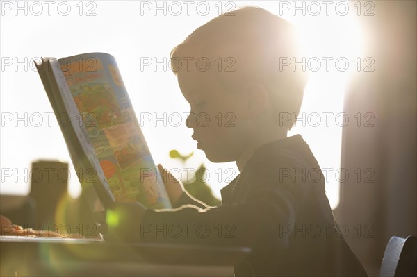 Symbolic photo: A little boy looks at a picture book. Berlin