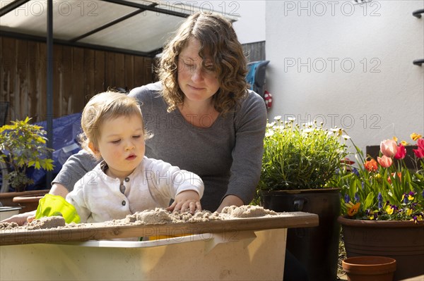 Subject: Mother playing with her child in a sandbox.
