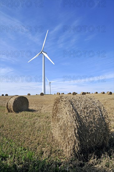 Wind turbines in mowed field with hay bales