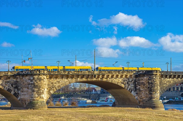 One of the well-known yellow trams of the Dresdner Verkehrsbetriebe is crossing the Augustusbruecke