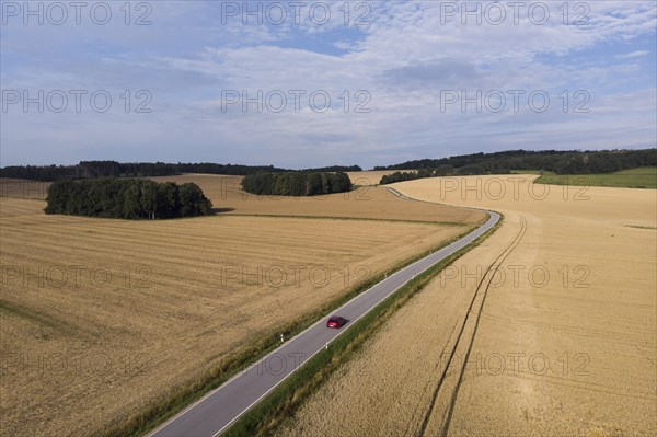 Aerial view of a country road with a red car in Koenigshain in Saxony.