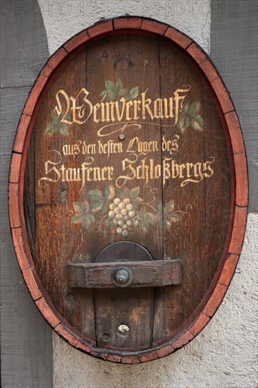 Old wine barrel on a house wall with artistic lettering and painting as a decorative advertising medium for wine sales