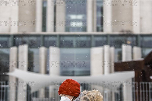 A person wearing a red cap and mouth guard stands out in front of the Federal Chancellery in front of the Federal-Laender on the further procedure of the Corona restrictions