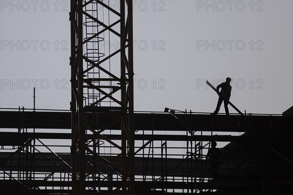 The silhouette of a scaffolder stands out on a construction site in Berlin