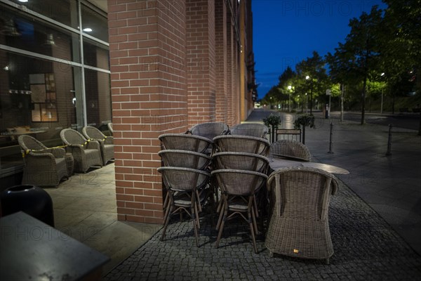 Unused furniture standing in front of a cafe at Potsdamer Platz in Berlin in the evening