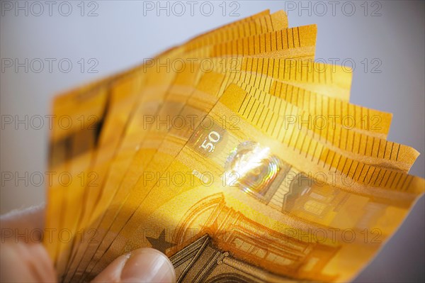 Symbolic photo on the subject of cash. 50 euro banknotes are held in one hand. Berlin