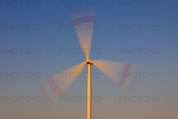 Spinning blades of wind turbine against blue sky