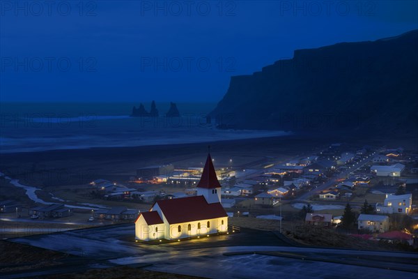 Illuminated Vikurkirkja church at the village Vik i Myrdal in winter