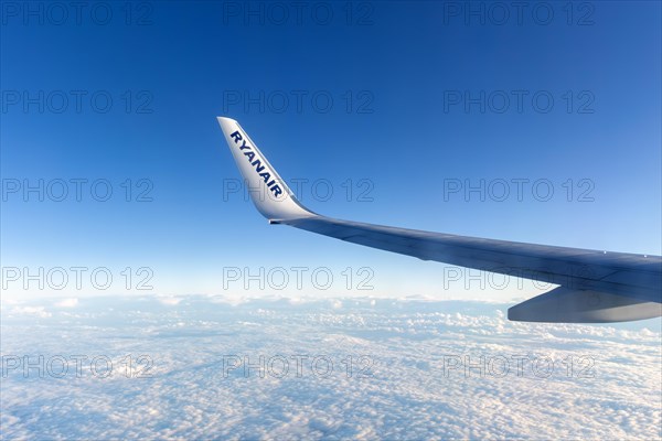 Wing tip of Ryanair airline Boeing 737 plane flying at high altitude above clouds