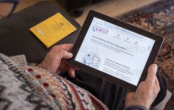 An elderly man holds an iPad with the open website of the patient service www.116117.de