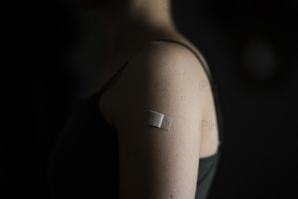 A plaster is stuck on the left upper arm of a woman vaccinated against Corona