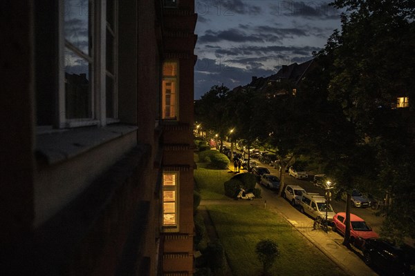 A street with parked cars stands out at blue hour in Berlin