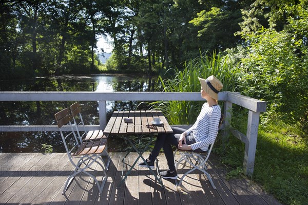 Woman sitting by a pond drinking coffee