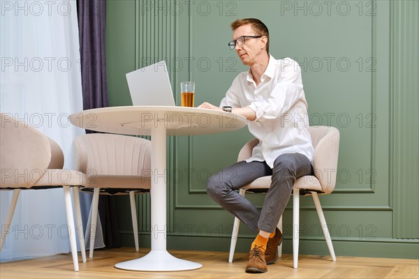 Middle aged man using laptop at home sitting in living room
